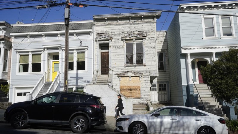 A pedestrian walks a dog past a recently sold Victorian home in San Francisco, Friday, Jan. 14, 2022. The decaying, 122-year-old Victorian marketed as 