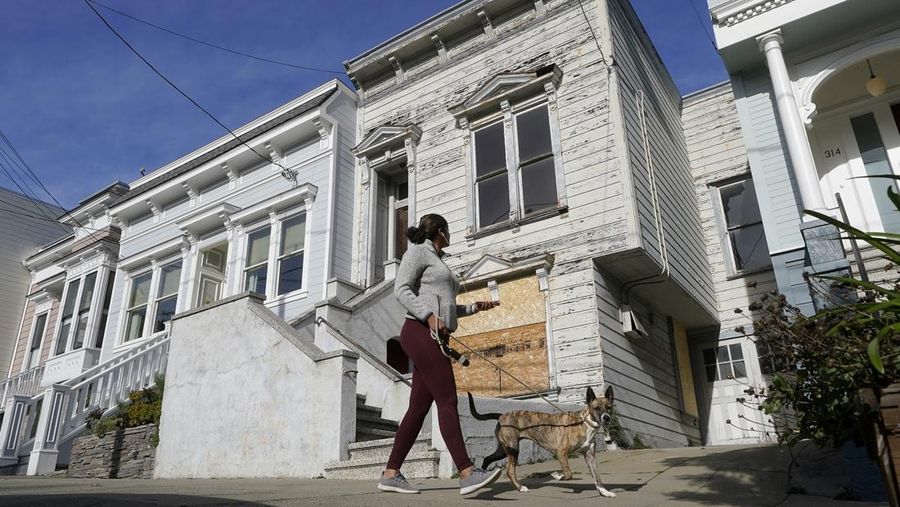 A pedestrian walks a dog past a recently sold Victorian home in San Francisco, Friday, Jan. 14, 2022. The decaying, 122-year-old Victorian marketed as 