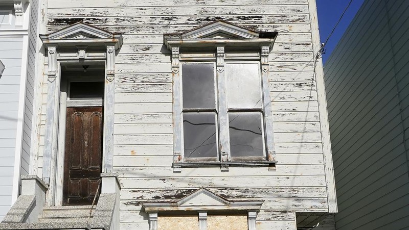 A pedestrian walks a dog past a recently sold Victorian home in San Francisco, Friday, Jan. 14, 2022. The decaying, 122-year-old Victorian marketed as 