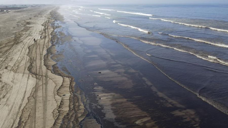 Oil floats in the water off Cavero beach in Ventanilla, Callao, Peru, Tuesday, Jan. 18, 2022, after high waves attributed to the eruption of an undersea volcano in Tonga caused an oil spill. The Peruvian Civil Defense Institute said in a press release that a ship was loading oil into La Pampilla refinery on the Pacific coast on Sunday when strong waves moved the boat and caused the spill. (AP Photo/Martin Mejia)