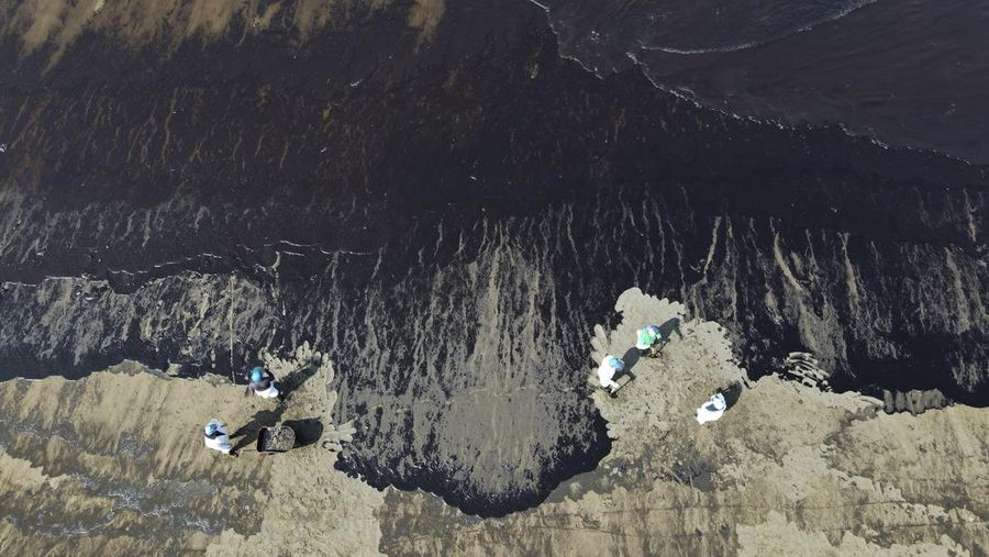 Oil floats in the water off Cavero beach in Ventanilla, Callao, Peru, Tuesday, Jan. 18, 2022, after high waves attributed to the eruption of an undersea volcano in Tonga caused an oil spill. The Peruvian Civil Defense Institute said in a press release that a ship was loading oil into La Pampilla refinery on the Pacific coast on Sunday when strong waves moved the boat and caused the spill. (AP Photo/Martin Mejia)