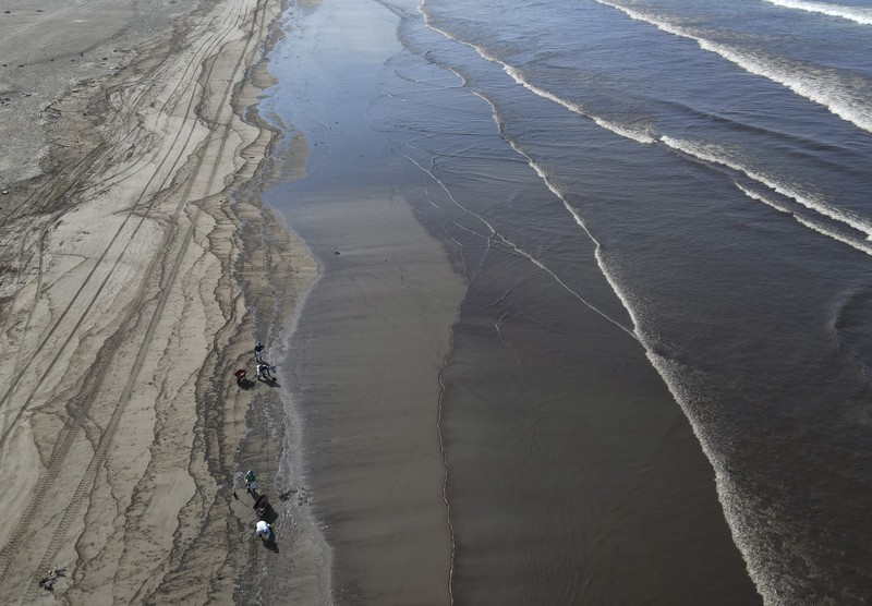 Oil floats in the water off Cavero beach in Ventanilla, Callao, Peru, Tuesday, Jan. 18, 2022, after high waves attributed to the eruption of an undersea volcano in Tonga caused an oil spill. The Peruvian Civil Defense Institute said in a press release that a ship was loading oil into La Pampilla refinery on the Pacific coast on Sunday when strong waves moved the boat and caused the spill. (AP Photo/Martin Mejia)