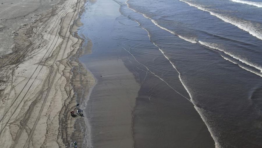 Oil floats in the water off Cavero beach in Ventanilla, Callao, Peru, Tuesday, Jan. 18, 2022, after high waves attributed to the eruption of an undersea volcano in Tonga caused an oil spill. The Peruvian Civil Defense Institute said in a press release that a ship was loading oil into La Pampilla refinery on the Pacific coast on Sunday when strong waves moved the boat and caused the spill. (AP Photo/Martin Mejia)