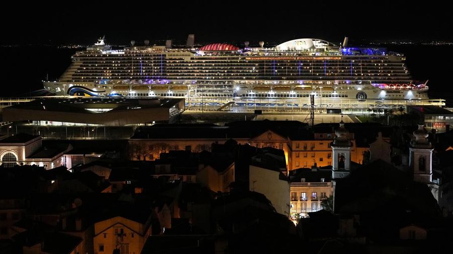 People stand on the deck of the German cruise ship AIDAnova docked in Lisbon, shortly before midnight, Friday, Dec. 31, 2021. According to news reports, the ship, which was on its way to Lanzarote, has been held back in Lisbon due to a coronavirus outbreak aboard. (AP Photo/Armando Franca)