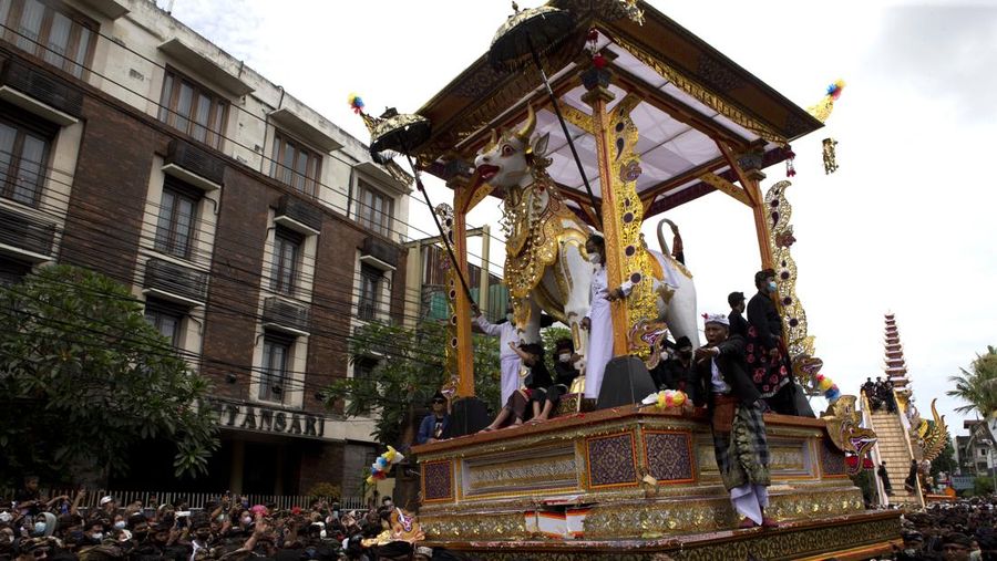 A crowd of people watch a giant sarcophagus in the form of a bull during a procession of King Ida Cokorda Pemecutan XI in Denpasar, Bali, Indonesia on Friday, Jan. 21, 2022. (AP Photo/Firdia Lisnawati)