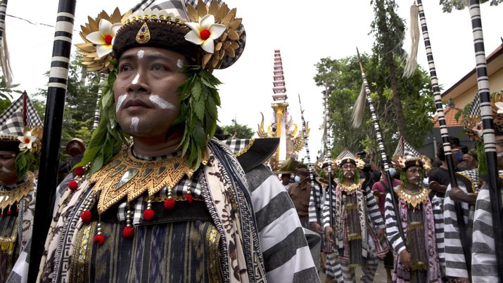 Men dressed in Balinese traditional warriors participate in a parade during a cremation ceremony of King Ida Cokorda Pemecutan XI in Denpasar, Bali, Indonesia on Friday, Jan. 21, 2022. (AP Photo/Firdia Lisnawati)