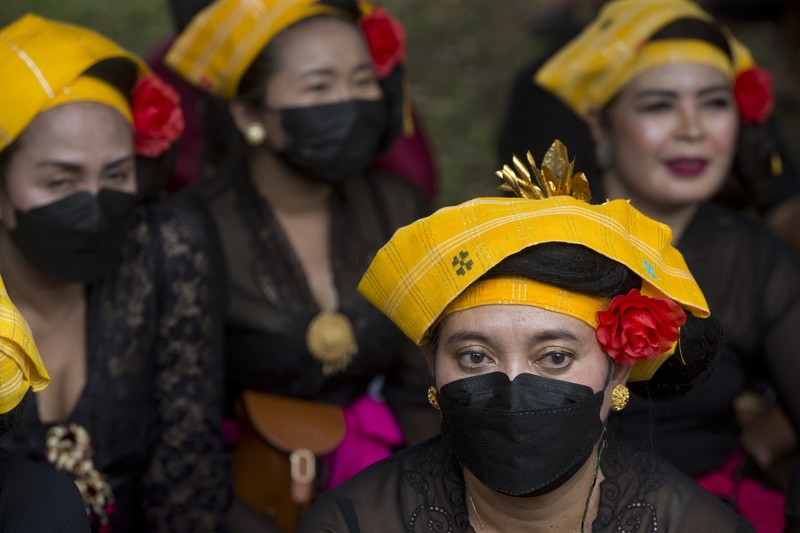 A crowd of people watch a giant sarcophagus in the form of a bull during a procession of King Ida Cokorda Pemecutan XI in Denpasar, Bali, Indonesia on Friday, Jan. 21, 2022. (AP Photo/Firdia Lisnawati)