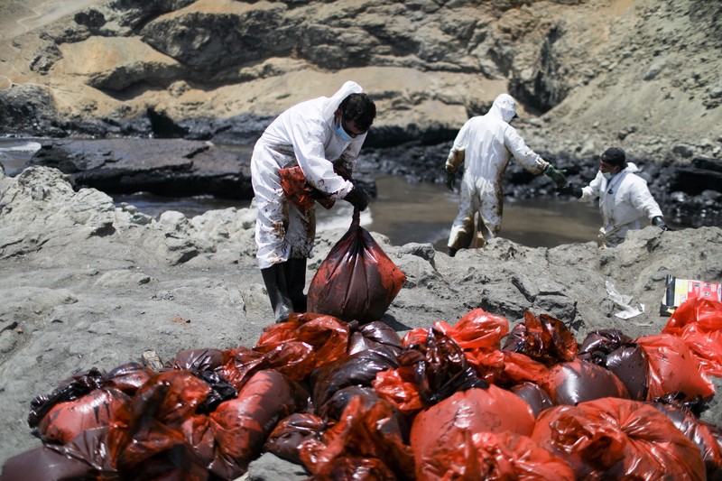 Otoritas setempat dan pekerja kilang La Pampilla, Peru, membersihkan tumpahan minyak di lepas pantai Ventanilla. Tumpahan minyak ini terjadi akibat gelombang tsunami yang dipicu letusan gunung api bawah laut di Tonga. (REUTERS/PILAR OLIVARES) Otoritas setempat dan pekerja kilang La Pampilla, Peru, membersihkan tumpahan minyak di lepas pantai Ventanilla. Tumpahan minyak ini terjadi akibat gelombang tsunami yang dipicu letusan gunung api bawah laut di Tonga. (REUTERS/PILAR OLIVARES)