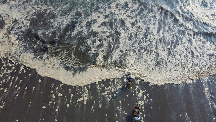 Otoritas setempat dan pekerja kilang La Pampilla, Peru, membersihkan tumpahan minyak di lepas pantai Ventanilla. Tumpahan minyak ini terjadi akibat gelombang tsunami yang dipicu letusan gunung api bawah laut di Tonga. (REUTERS/PILAR OLIVARES)