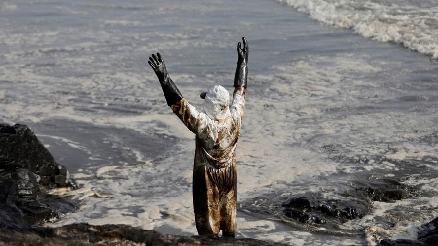 Otoritas setempat dan pekerja kilang La Pampilla, Peru, membersihkan tumpahan minyak di lepas pantai Ventanilla. Tumpahan minyak ini terjadi akibat gelombang tsunami yang dipicu letusan gunung api bawah laut di Tonga. (REUTERS/PILAR OLIVARES)