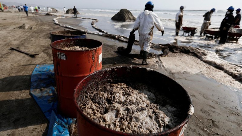 Otoritas setempat dan pekerja kilang La Pampilla, Peru, membersihkan tumpahan minyak di lepas pantai Ventanilla. Tumpahan minyak ini terjadi akibat gelombang tsunami yang dipicu letusan gunung api bawah laut di Tonga. (REUTERS/PILAR OLIVARES)