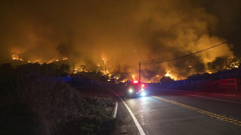 Mobil melintas saat api kebakaran Colorado membakar di sepanjang Highway 1 dekat Big Sur, California, Sabtu, 22 Januari 2022. (AP Photo/Nic Coury)