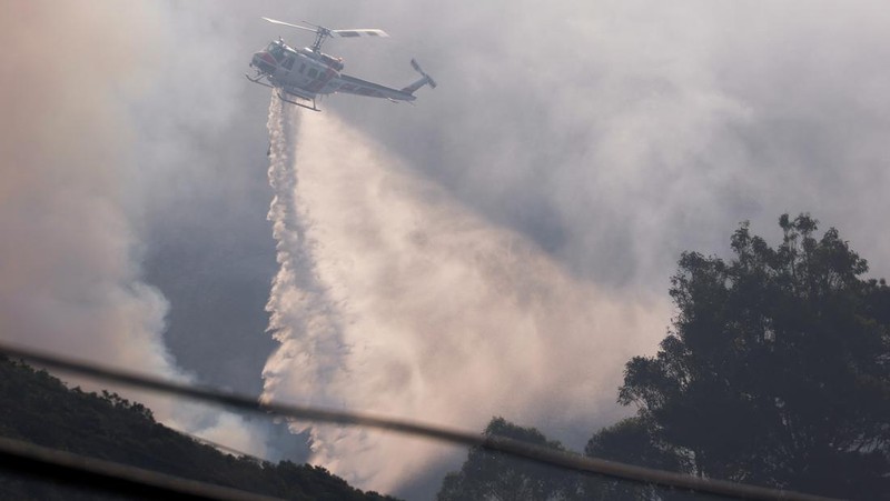 Mobil melintas saat api kebakaran Colorado membakar di sepanjang Highway 1 dekat Big Sur, California, Sabtu, 22 Januari 2022. (AP Photo/Nic Coury)