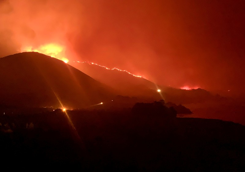 Mobil melintas saat api kebakaran Colorado membakar di sepanjang Highway 1 dekat Big Sur, California, Sabtu, 22 Januari 2022. (AP Photo/Nic Coury)