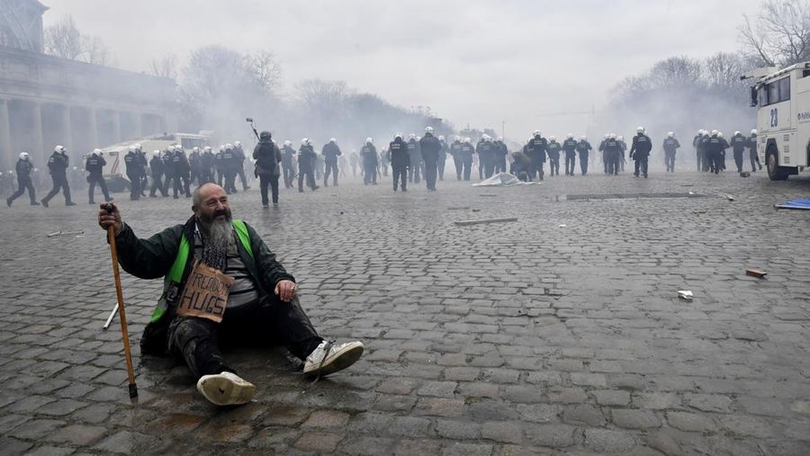 Seorang pengunjuk rasa berbaris dengan salib di dekat markas besar Uni Eropa selama demonstrasi menentang vaksin COVID-19 di Brussels, Minggu (23/1/2022). Demonstran berkumpul di ibukota Belgia untuk memprotes apa yang mereka anggap sebagai tindakan yang terlalu ekstrem oleh pemerintah untuk memerangi COVID -19 pandemi, termasuk izin vaksin yang mengatur akses ke tempat dan kegiatan tertentu dan kemungkinan vaksin wajib. Cross berbunyi 'Kebenaran yang membuat kita dibohongi'. (AP Photo/Geert Vanden Wijngaert)