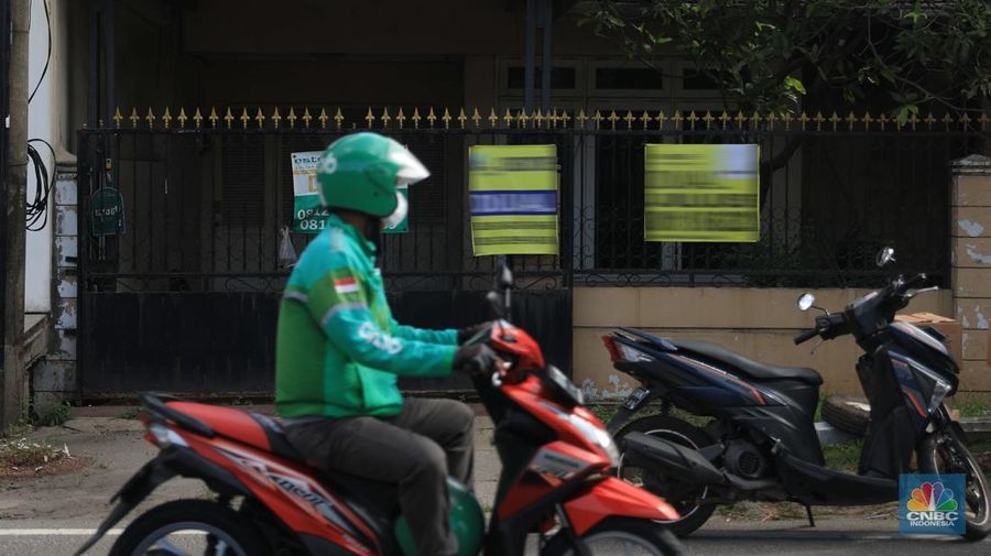 Pengendara motor melintas di depan rumah yg dijual di kawasan Kelapa Gading, Jakarta, Senin, 24/1/2022. Sektor properti di tahun 2021 lalu masih mengalami tekanan meski sudah lebih baik dari tahun 2020. Kala itu, harga tanah mengalami penurunan cukup dalam. Memasuki tahun 2022, arah perbaikan diakui mulai terlihat namun masih jauh dari normal. Pasalnya, harga-harga tanah termasuk di kawasan Kelapa Gading masih terpangkas hingga jutaan rupiah. Ketua DPC Asosiasi Real Estate Broker Indonesia (AREBI) Jakarta Utara Jopie Hori mengakui memang masih ada penurunan harga tanah. Pantauan CNBC Indonesia dilapangan beberapa toko dijual dan disewa dari berbagai macam loan properti yang berbeda. Meski dikenal kerap tergenang banjir, namun tanah atau hunian di wilayah Kelapa Gading tetap menjadi incaran banyak orang, utamanya mereka yang biasa beraktivitas di wilayah tersebut. Meski banyak dicari namun harganya tetap terkoreksi, terutama di wilayah yang paling mahal di kawasan Jakarta Utara, misalnya perumahan Bukit Gading Villa kawasan Kelapa Gading.  (CNBC Indonesia/ Muhammad Sabk)