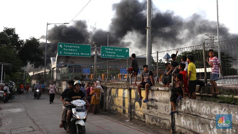 Petugas pemadam kebakaran melakukan pemadaman api yang membakar hudang rental motor listrik MIGO di kawasan  Meruya Bara, Jakarta barat, Senin (24/1/2022). Sebanyak enam mobil damkar dikerahkan dalam insiden ini. Belum ada info resmi dari pemilik gudang. Menurut warga sekitar 