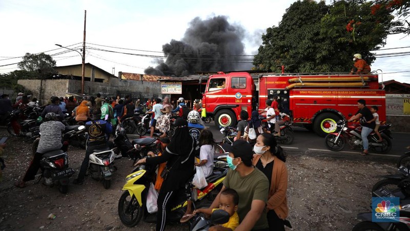 Petugas pemadam kebakaran melakukan pemadaman api yang membakar hudang rental motor listrik MIGO di kawasan  Meruya Bara, Jakarta barat, Senin (24/1/2022). Sebanyak enam mobil damkar dikerahkan dalam insiden ini. Belum ada info resmi dari pemilik gudang. Menurut warga sekitar 