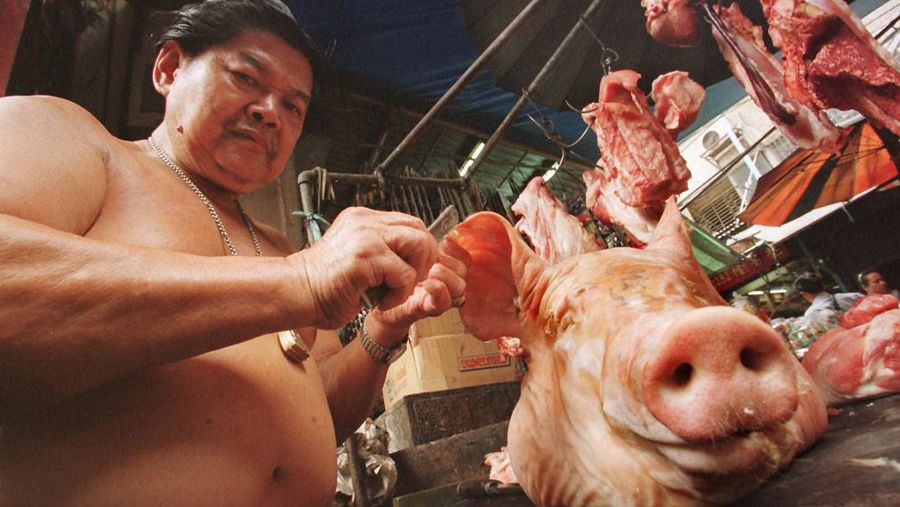Seorang tpenjual daging memotong kuping babi di pasar Bangkok Selasa(7/10/1997). Biasanya tidak dikonsumsi, wajah babi digunakan selama ibadah mengikuti cerita rakyat tradisional Brahman dan Hindu yang dewa yang kuat senang dengan persembahan hewan yang baru dibunuh. (AP Photo/Charles Dharapak)