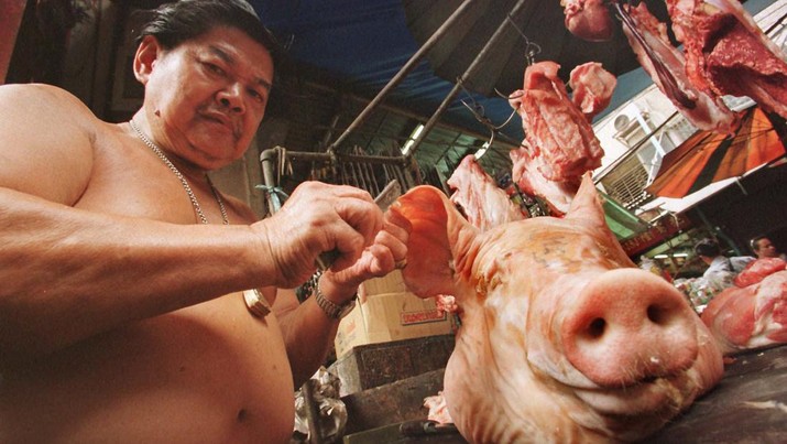 Seorang tpenjual daging memotong kuping babi di pasar Bangkok Selasa(7/10/1997). Biasanya tidak dikonsumsi, wajah babi digunakan selama ibadah mengikuti cerita rakyat tradisional Brahman dan Hindu yang dewa yang kuat senang dengan persembahan hewan yang baru dibunuh. (AP Photo/Charles Dharapak)