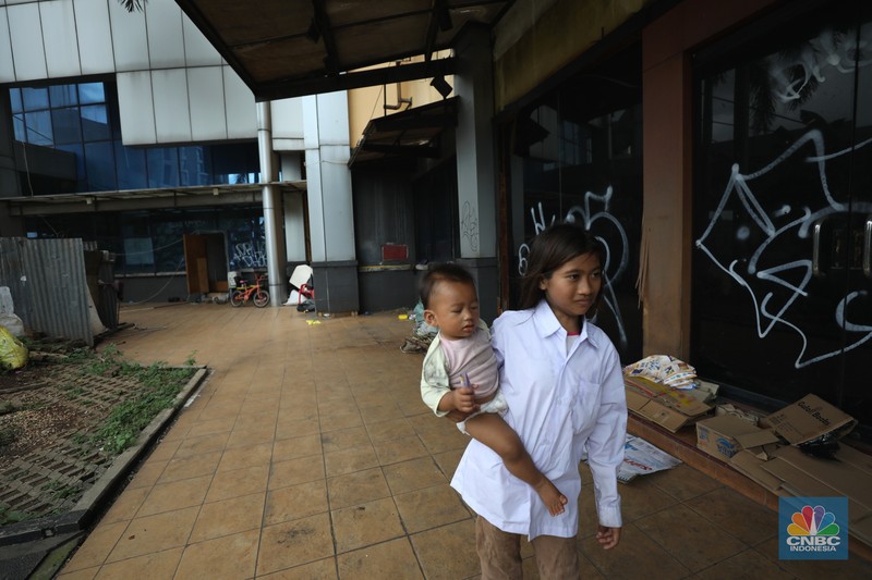 Sejumlah anak melewati bangunan Serpong Plaza yang kosong tak berpenghuni di Kawasan Jalan raya Serpong, Tangerang, Selasa (25/1/2022). 
Mall Serpong yang berada di Jalan Raya Serpong, Serpong, Tangerang Selatan ini sudah tidak digunakan dan terkesan menyeramkan.
Didepan lokasi terpasang pembatas seng dan benner bertuliskan 