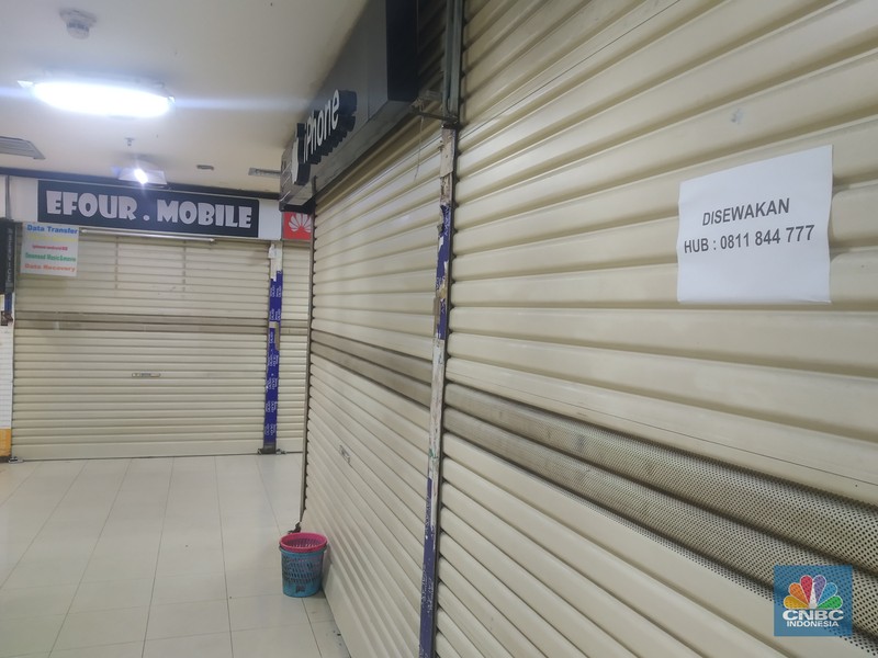 Suasana Mall Ambassador yang Sepi Petugas kebersihan mengepel lantai di kawasan mall Ambassador, Jakarta, Selasa, 25/1/2022. Pandemi Covid-19 telah membuat industri ritel, terutama pusat perbelanjaan sulit untuk bangkit. Mutasi baru varian Covid-19 yang terus menerus muncul membuat orang kini lebih memilih untuk tidak bepergian. Akibatnya, mal-mal di DKI Jakarta seperti di kawasan Mall Ambassador Jakarta Selatan Di mana pusat perbelanjaan tersebut kebanyakan berisi pedagang elektronik, seperti handphone, laptop, kamera, serta aksesoris lain. Kini harus menghadapi kenyataan sepi pengunjung. Banyak kini kios-kios di sejumlah pusat perbelanjaan di DKI Jakarta dijual atau disewakan.
Saat CNBC Indonesia menyambangi Mal Ambassador yang kebanyakan berisi pedagang elektronik, ada beberapa toko yang tutup di lantai 3. Terlihat pada gerai toko itu terpampang selembaran info bahwa toko tersebut hendak dijual ataupun disewakan. Meskipun pembeli terlihat cukup ramai di lantai dasar. Salah satu pedagang, Bjeh mengatakan bahwa tutupnya beberapa toko ini, karena jarangnya pembeli. Oleh karenanya pedagang harus rela meninggalkan tokonya tersebut. Berdasarkan pengamatan CNBC Indonesia, memang banyak gerai yang dijual hingga dikontrakkan ke penyewa yang berminat. Namun, itu bukan perkara mudah karena banyak pelaku usaha yang menahan dana untuk tidak berinvestasi di pusat perbelanjaan. Menanggapi fenomena mal-mal legendaris di Jakarta yang sepi, Ketua Umum Himpunan Penyewa Pusat Perbelanjaan Indonesia Budihardjo Iduansjah mengungkapkan, banyaknya tenant atau penyewa menutup gerai disebabkan ekosistem ekonomi di mal itu sudah tidak lagi bergairah. (CNBC Indonesia/ Muhammad Sabki)