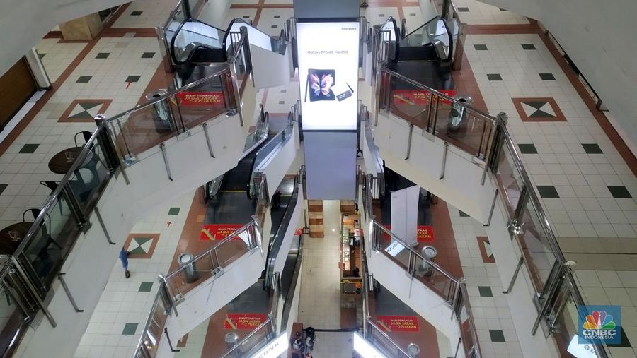 Petugas kebersihan mengepel lantai di kawasan mall Ambassador, Jakarta, Selasa, 25/1/2022. Pandemi Covid-19 telah membuat industri ritel, terutama pusat perbelanjaan sulit untuk bangkit. Mutasi baru varian Covid-19 yang terus menerus muncul membuat orang kini lebih memilih untuk tidak bepergian. Akibatnya, mal-mal di DKI Jakarta seperti di kawasan Mall Ambassador Jakarta Selatan Di mana pusat perbelanjaan tersebut kebanyakan berisi pedagang elektronik, seperti handphone, laptop, kamera, serta aksesoris lain. Kini harus menghadapi kenyataan sepi pengunjung. Banyak kini kios-kios di sejumlah pusat perbelanjaan di DKI Jakarta dijual atau disewakan.
Saat CNBC Indonesia menyambangi Mal Ambassador yang kebanyakan berisi pedagang elektronik, ada beberapa toko yang tutup di lantai 3. Terlihat pada gerai toko itu terpampang selembaran info bahwa toko tersebut hendak dijual ataupun disewakan. Meskipun pembeli terlihat cukup ramai di lantai dasar. Salah satu pedagang, Bjeh mengatakan bahwa tutupnya beberapa toko ini, karena jarangnya pembeli. Oleh karenanya pedagang harus rela meninggalkan tokonya tersebut. Berdasarkan pengamatan CNBC Indonesia, memang banyak gerai yang dijual hingga dikontrakkan ke penyewa yang berminat. Namun, itu bukan perkara mudah karena banyak pelaku usaha yang menahan dana untuk tidak berinvestasi di pusat perbelanjaan. Menanggapi fenomena mal-mal legendaris di Jakarta yang sepi, Ketua Umum Himpunan Penyewa Pusat Perbelanjaan Indonesia Budihardjo Iduansjah mengungkapkan, banyaknya tenant atau penyewa menutup gerai disebabkan ekosistem ekonomi di mal itu sudah tidak lagi bergairah. (CNBC Indonesia/ Muhammad Sabki)