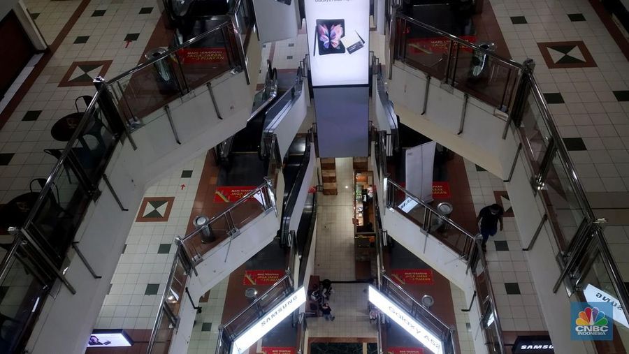 Petugas kebersihan mengepel lantai di kawasan mall Ambassador, Jakarta, Selasa, 25/1/2022. Pandemi Covid-19 telah membuat industri ritel, terutama pusat perbelanjaan sulit untuk bangkit. Mutasi baru varian Covid-19 yang terus menerus muncul membuat orang kini lebih memilih untuk tidak bepergian. Akibatnya, mal-mal di DKI Jakarta seperti di kawasan Mall Ambassador Jakarta Selatan Di mana pusat perbelanjaan tersebut kebanyakan berisi pedagang elektronik, seperti handphone, laptop, kamera, serta aksesoris lain. Kini harus menghadapi kenyataan sepi pengunjung. Banyak kini kios-kios di sejumlah pusat perbelanjaan di DKI Jakarta dijual atau disewakan.
Saat CNBC Indonesia menyambangi Mal Ambassador yang kebanyakan berisi pedagang elektronik, ada beberapa toko yang tutup di lantai 3. Terlihat pada gerai toko itu terpampang selembaran info bahwa toko tersebut hendak dijual ataupun disewakan. Meskipun pembeli terlihat cukup ramai di lantai dasar. Salah satu pedagang, Bjeh mengatakan bahwa tutupnya beberapa toko ini, karena jarangnya pembeli. Oleh karenanya pedagang harus rela meninggalkan tokonya tersebut. Berdasarkan pengamatan CNBC Indonesia, memang banyak gerai yang dijual hingga dikontrakkan ke penyewa yang berminat. Namun, itu bukan perkara mudah karena banyak pelaku usaha yang menahan dana untuk tidak berinvestasi di pusat perbelanjaan. Menanggapi fenomena mal-mal legendaris di Jakarta yang sepi, Ketua Umum Himpunan Penyewa Pusat Perbelanjaan Indonesia Budihardjo Iduansjah mengungkapkan, banyaknya tenant atau penyewa menutup gerai disebabkan ekosistem ekonomi di mal itu sudah tidak lagi bergairah. (CNBC Indonesia/ Muhammad Sabki)