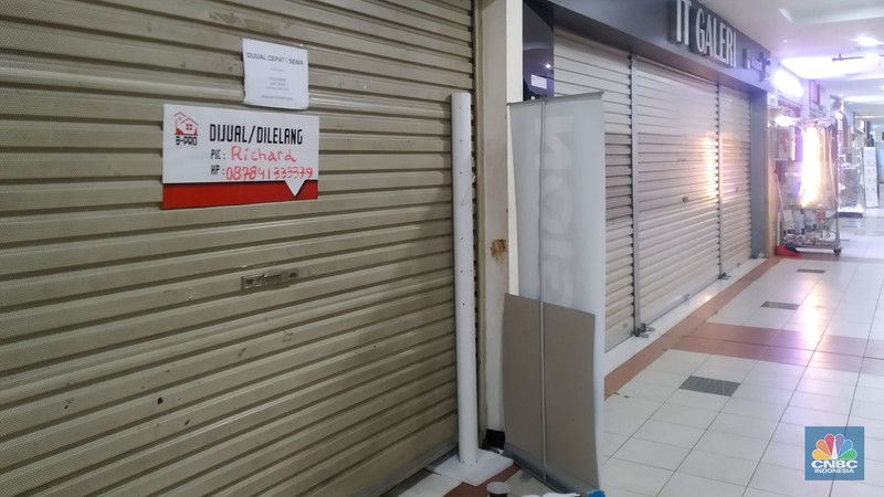 Suasana Mall Ambassador yang Sepi Petugas kebersihan mengepel lantai di kawasan mall Ambassador, Jakarta, Selasa, 25/1/2022. Pandemi Covid-19 telah membuat industri ritel, terutama pusat perbelanjaan sulit untuk bangkit. Mutasi baru varian Covid-19 yang terus menerus muncul membuat orang kini lebih memilih untuk tidak bepergian. Akibatnya, mal-mal di DKI Jakarta seperti di kawasan Mall Ambassador Jakarta Selatan Di mana pusat perbelanjaan tersebut kebanyakan berisi pedagang elektronik, seperti handphone, laptop, kamera, serta aksesoris lain. Kini harus menghadapi kenyataan sepi pengunjung. Banyak kini kios-kios di sejumlah pusat perbelanjaan di DKI Jakarta dijual atau disewakan.
Saat CNBC Indonesia menyambangi Mal Ambassador yang kebanyakan berisi pedagang elektronik, ada beberapa toko yang tutup di lantai 3. Terlihat pada gerai toko itu terpampang selembaran info bahwa toko tersebut hendak dijual ataupun disewakan. Meskipun pembeli terlihat cukup ramai di lantai dasar. Salah satu pedagang, Bjeh mengatakan bahwa tutupnya beberapa toko ini, karena jarangnya pembeli. Oleh karenanya pedagang harus rela meninggalkan tokonya tersebut. Berdasarkan pengamatan CNBC Indonesia, memang banyak gerai yang dijual hingga dikontrakkan ke penyewa yang berminat. Namun, itu bukan perkara mudah karena banyak pelaku usaha yang menahan dana untuk tidak berinvestasi di pusat perbelanjaan. Menanggapi fenomena mal-mal legendaris di Jakarta yang sepi, Ketua Umum Himpunan Penyewa Pusat Perbelanjaan Indonesia Budihardjo Iduansjah mengungkapkan, banyaknya tenant atau penyewa menutup gerai disebabkan ekosistem ekonomi di mal itu sudah tidak lagi bergairah. (CNBC Indonesia/ Muhammad Sabki)