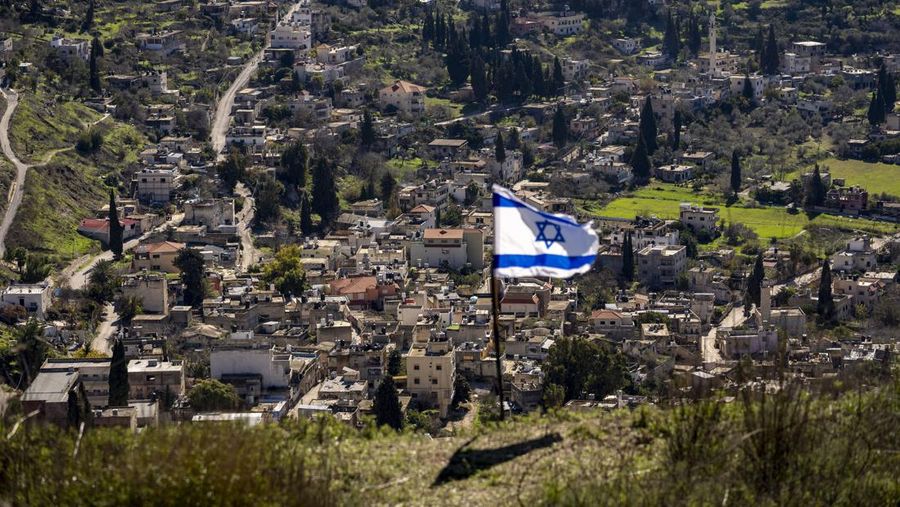The Palestinian village of Burqa is seen as an Israeli flag is placed in the Jewish West Bank outpost of Homesh, Monday, Jan. 17, 2022. Palestinian residents of Burqa say the settlers' continued presence in Homesh, which was officially dismantled in 2005, makes it difficult to access their land and move safely in and out of their village. (AP Photo/Ariel Schalit)
