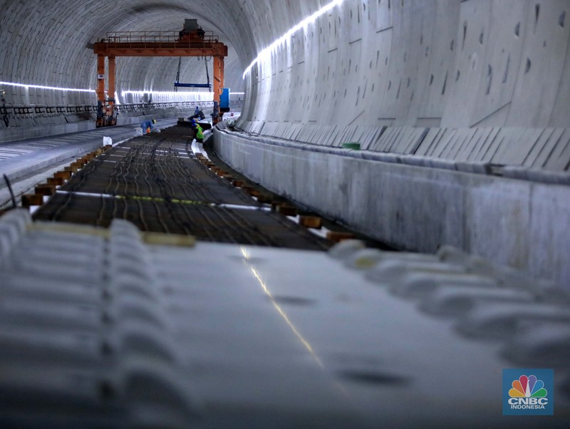 Pekerja Mengerjakan Proyek Tunnel #1 Kereta Cepat Jakarta Bandung Sepanjang 1.885 meter atau 1,8 kilometer yang berlokasi di Jalan Tol Jakarta-Cikampek KM 5+500, Kamis, (27/1/2022). Tunnel 1 merupakan terowongan dengan dua lintasan kereta cepat yang berlokasi di area Halim dan berjarak 2.5 kilometer dari Stasiun Kereta Cepat.

Tunnel 1 dirancang sepanjang 1.885 meter dan dibangun dengan metode Tunnel Boring Machine (TBM). Terowongan ini melintang menembus bagian bawah Jalan Tol Jakarta-Cikampek.

Pembangunan proyek Tunnel 1 ini dilakukan menggunakan mesin bor atau Tunnel Boring Machine (TBM). TBM merupakan mesin bor pembuat terowongan yang didatangkan langsung dari negeri China, untuk membuat struktur Tunnel 1 Kereta Cepat Jakarta Bandung. TBM yang digunakan memiliki diameter 13,23 meter dengan panjang 102,3 meter, berat 2.600 ton dan menjadi mesin bor TBM terbesar se-Asia Tenggara.

TBM kereta cepat ini beroperasi menggali struktur tunnel 1 dengan rata-rata 113 meter per bulan. Saat beroperasi maksimum, TBM kereta cepat mampu menggali hingga 322 meter dalam satu bulan.

Ukuran TBM yang sangat besar ini diganjar Museum Rekor Dunia Indonesia (MURI) sebagai mesin bor terbesar penggali terowongan yang ada di Indonesia. Dari 5 tunnel yang telah dibangun untuk proyek KCJB, hanya Tunnel 1 Halim yang dibangun menggunakan mesin bor TBM. (CNBC Indonesia/ Muhammad Sabki)