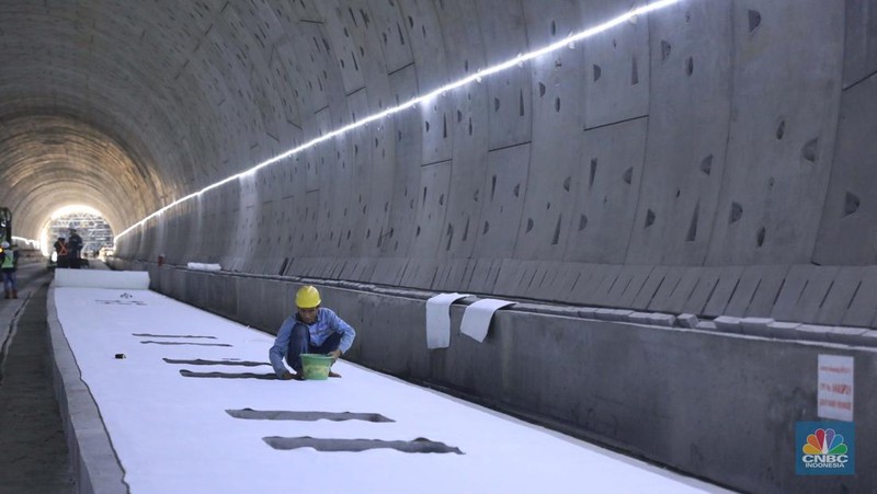 Pekerja Mengerjakan Proyek Tunnel #1 Kereta Cepat Jakarta Bandung Sepanjang 1.885 meter atau 1,8 kilometer yang berlokasi di Jalan Tol Jakarta-Cikampek KM 5+500, Kamis, (27/1/2022). Tunnel 1 merupakan terowongan dengan dua lintasan kereta cepat yang berlokasi di area Halim dan berjarak 2.5 kilometer dari Stasiun Kereta Cepat.

Tunnel 1 dirancang sepanjang 1.885 meter dan dibangun dengan metode Tunnel Boring Machine (TBM). Terowongan ini melintang menembus bagian bawah Jalan Tol Jakarta-Cikampek.

Pembangunan proyek Tunnel 1 ini dilakukan menggunakan mesin bor atau Tunnel Boring Machine (TBM). TBM merupakan mesin bor pembuat terowongan yang didatangkan langsung dari negeri China, untuk membuat struktur Tunnel 1 Kereta Cepat Jakarta Bandung. TBM yang digunakan memiliki diameter 13,23 meter dengan panjang 102,3 meter, berat 2.600 ton dan menjadi mesin bor TBM terbesar se-Asia Tenggara.

TBM kereta cepat ini beroperasi menggali struktur tunnel 1 dengan rata-rata 113 meter per bulan. Saat beroperasi maksimum, TBM kereta cepat mampu menggali hingga 322 meter dalam satu bulan.

Ukuran TBM yang sangat besar ini diganjar Museum Rekor Dunia Indonesia (MURI) sebagai mesin bor terbesar penggali terowongan yang ada di Indonesia. Dari 5 tunnel yang telah dibangun untuk proyek KCJB, hanya Tunnel 1 Halim yang dibangun menggunakan mesin bor TBM. (CNBC Indonesia/ Muhammad Sabki)