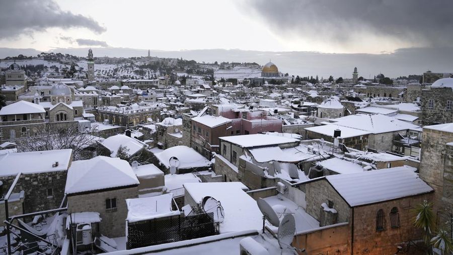 Warga Palestina menikmati salju di sebelah Masjid Kubah Batu di kompleks Masjid Al Aqsa di Kota Tua Yerusalem, Kamis (27/1/2022). Hujan salju yang jarang melanda sebagian wilayah Israel dan Tepi Barat, menutup sekolah dan bisnis. (AP Photo/Mahmoud Illean)