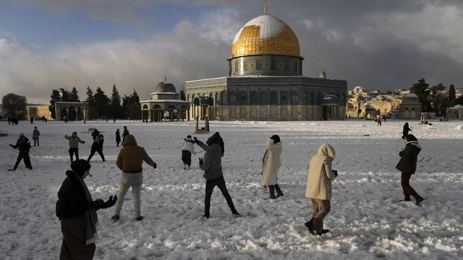 Warga Palestina menikmati salju di sebelah Masjid Kubah Batu di kompleks Masjid Al Aqsa di Kota Tua Yerusalem, Kamis (27/1/2022). Hujan salju yang jarang melanda sebagian wilayah Israel dan Tepi Barat, menutup sekolah dan bisnis. (AP Photo/Mahmoud Illean)