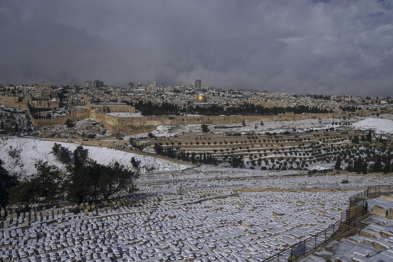 Warga Palestina menikmati salju di sebelah Masjid Kubah Batu di kompleks Masjid Al Aqsa di Kota Tua Yerusalem, Kamis (27/1/2022). Hujan salju yang jarang melanda sebagian wilayah Israel dan Tepi Barat, menutup sekolah dan bisnis. (AP Photo/Mahmoud Illean)