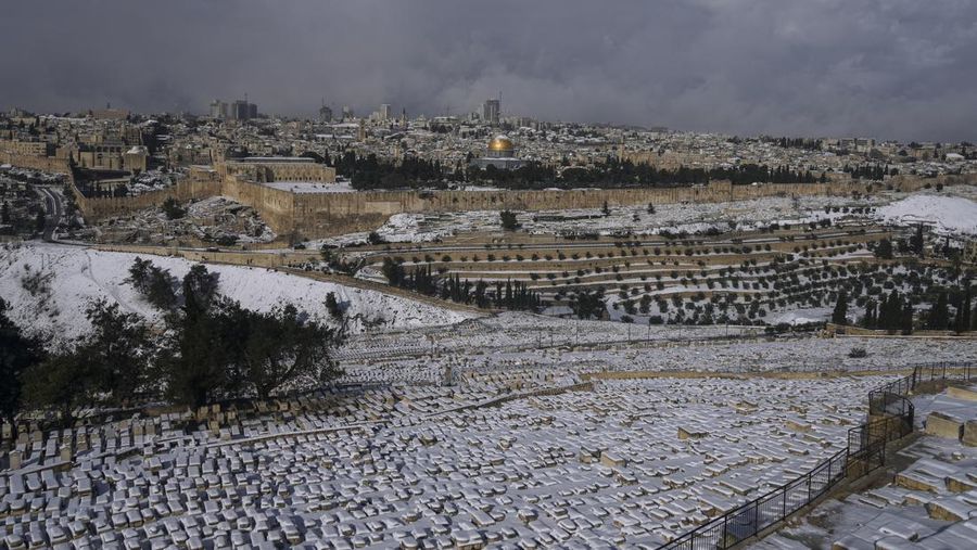 Warga Palestina menikmati salju di sebelah Masjid Kubah Batu di kompleks Masjid Al Aqsa di Kota Tua Yerusalem, Kamis (27/1/2022). Hujan salju yang jarang melanda sebagian wilayah Israel dan Tepi Barat, menutup sekolah dan bisnis. (AP Photo/Mahmoud Illean)