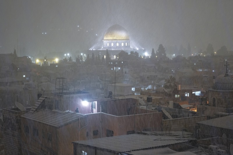 Warga Palestina menikmati salju di sebelah Masjid Kubah Batu di kompleks Masjid Al Aqsa di Kota Tua Yerusalem, Kamis (27/1/2022). Hujan salju yang jarang melanda sebagian wilayah Israel dan Tepi Barat, menutup sekolah dan bisnis. (AP Photo/Mahmoud Illean)