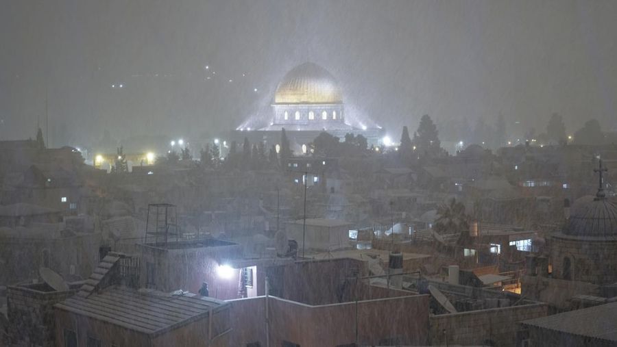 Warga Palestina menikmati salju di sebelah Masjid Kubah Batu di kompleks Masjid Al Aqsa di Kota Tua Yerusalem, Kamis (27/1/2022). Hujan salju yang jarang melanda sebagian wilayah Israel dan Tepi Barat, menutup sekolah dan bisnis. (AP Photo/Mahmoud Illean)
