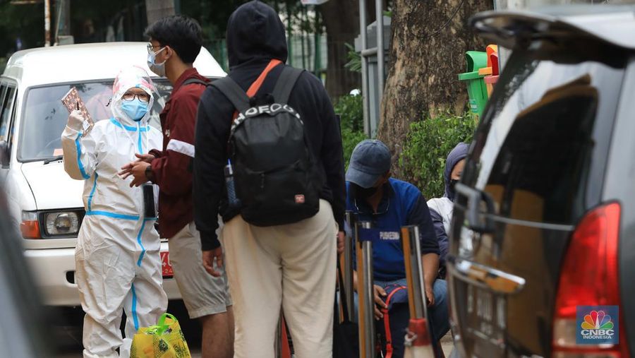 Petugas menggunakan Alat Pelindung Diri (APD) mendata pasien Covid-19 untuk di evakuasi masuk ke dalam bus sekolah di Puskesmas Tebet, Jakarta, Kamis (3/2/2022). (CNBC Indonesia/Muhammad Sabki)