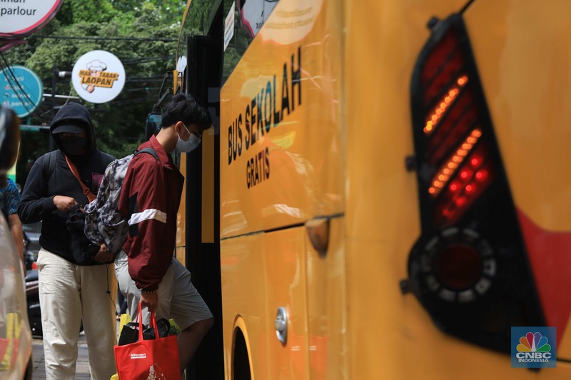 Petugas menggunakan Alat Pelindung Diri (APD) mendata pasien Covid-19 untuk di evakuasi masuk ke dalam bus sekolah di Puskesmas Tebet, Jakarta, Kamis (3/2/2022). (CNBC Indonesia/Muhammad Sabki)