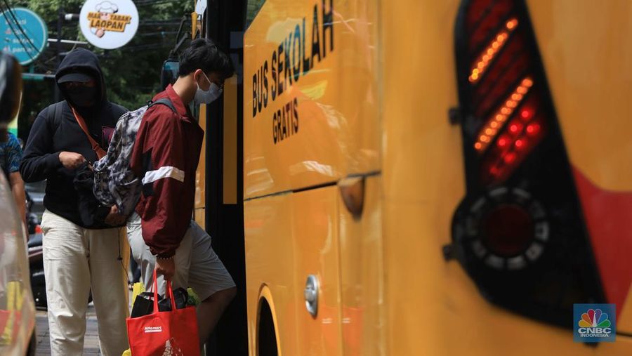 Petugas menggunakan Alat Pelindung Diri (APD) mendata pasien Covid-19 untuk di evakuasi masuk ke dalam bus sekolah di Puskesmas Tebet, Jakarta, Kamis (3/2/2022). (CNBC Indonesia/Muhammad Sabki)