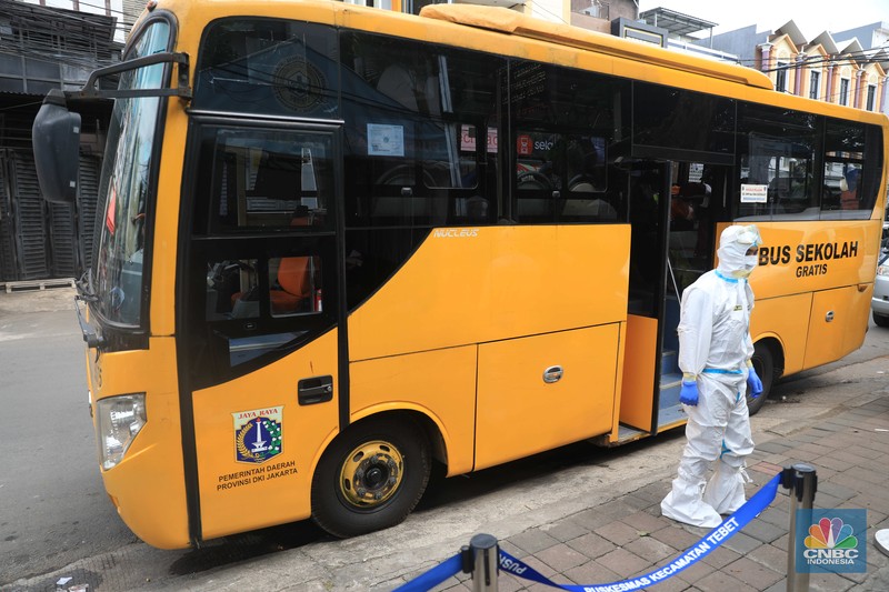 Petugas menggunakan Alat Pelindung Diri (APD) mendata pasien Covid-19 untuk di evakuasi masuk ke dalam bus sekolah di Puskesmas Tebet, Jakarta, Kamis (3/2/2022). (CNBC Indonesia/Muhammad Sabki)