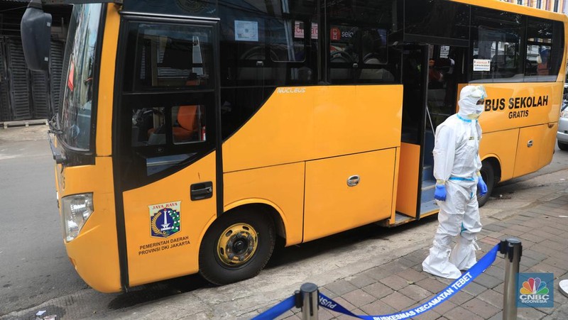 Petugas menggunakan Alat Pelindung Diri (APD) mendata pasien Covid-19 untuk di evakuasi masuk ke dalam bus sekolah di Puskesmas Tebet, Jakarta, Kamis (3/2/2022). (CNBC Indonesia/Muhammad Sabki)
