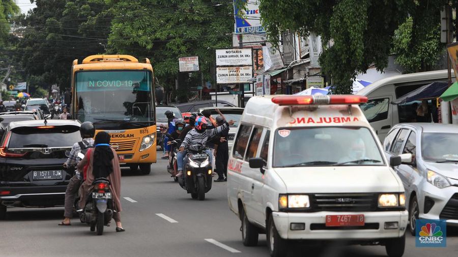 Petugas menggunakan Alat Pelindung Diri (APD) mendata pasien Covid-19 untuk di evakuasi masuk ke dalam bus sekolah di Puskesmas Tebet, Jakarta, Kamis (3/2/2022). (CNBC Indonesia/Muhammad Sabki)