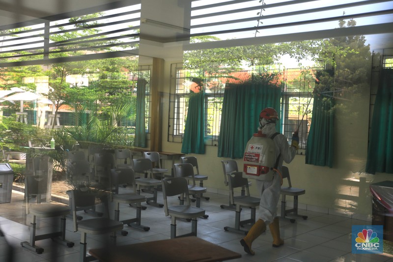 Petugas PMI menyemprotkan disinfektan di salah satu ruang kelas di SMPN 97, Jakarta, Kamis (3/2/2022). (CNBC Indonesia/Muhammad Sabki)