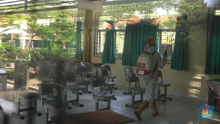 Petugas PMI menyemprotkan disinfektan di salah satu ruang kelas di SMPN 97, Jakarta, Kamis (3/2/2022). (CNBC Indonesia/Muhammad Sabki)