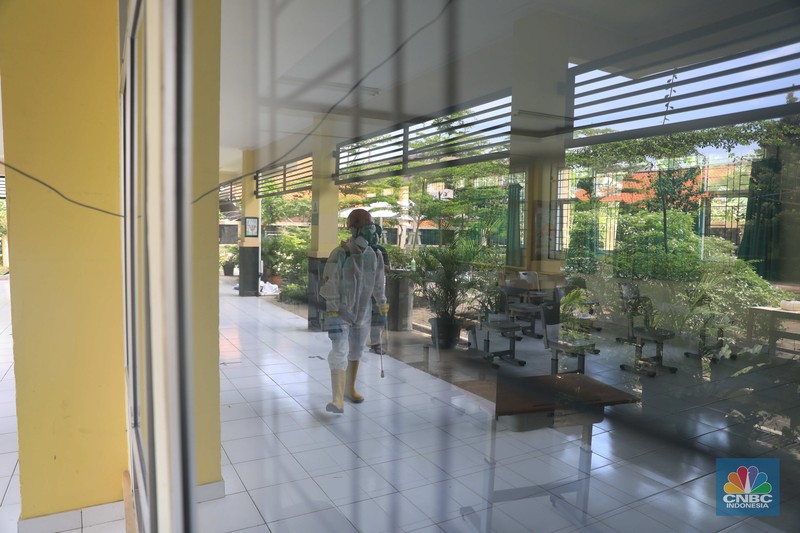 Petugas PMI menyemprotkan disinfektan di salah satu ruang kelas di SMPN 97, Jakarta, Kamis (3/2/2022). (CNBC Indonesia/Muhammad Sabki)