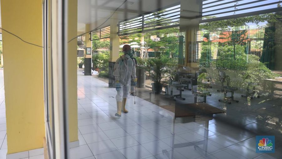 Petugas PMI menyemprotkan disinfektan di salah satu ruang kelas di SMPN 97, Jakarta, Kamis (3/2/2022). (CNBC Indonesia/Muhammad Sabki)