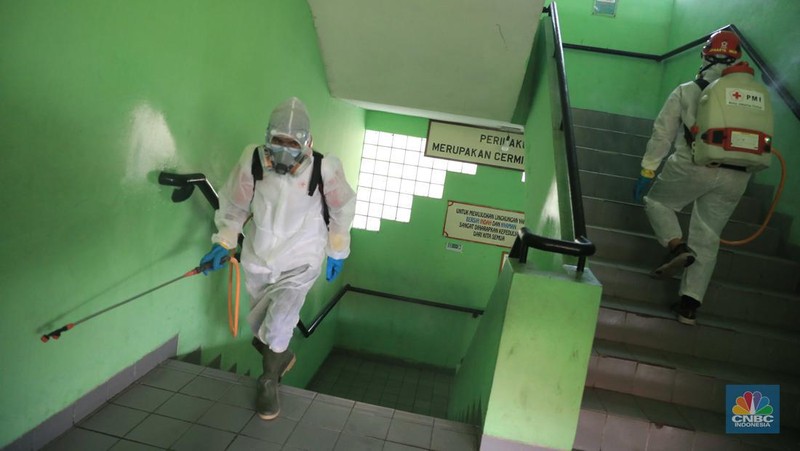 Petugas PMI menyemprotkan disinfektan di salah satu ruang kelas di SMPN 97, Jakarta, Kamis (3/2/2022). (CNBC Indonesia/Muhammad Sabki)