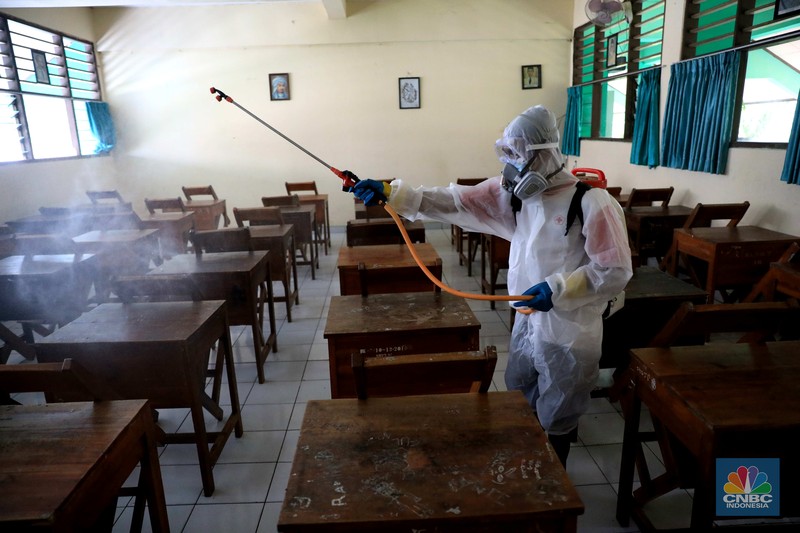 Petugas PMI menyemprotkan disinfektan di salah satu ruang kelas di SMPN 97, Jakarta, Kamis (3/2/2022). (CNBC Indonesia/Muhammad Sabki)